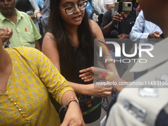 A doctor is tying Rakhis, or a traditional Indian sacred thread, on the wrist of a Kolkata Police officer during a protest rally for the R G...