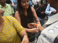 A doctor is tying Rakhis, or a traditional Indian sacred thread, on the wrist of a Kolkata Police officer during a protest rally for the R G...