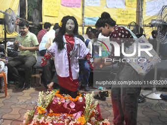 A doctor is tying Rakhis, or a traditional Indian sacred thread, on the wrist of a clay statue of a female doctor depicting a victim of rape...