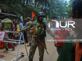 An Indian Paramilitary soldier is gesturing as Hindu devotees are arriving to pay obeisance on the occasion of the Raksha Bandhan festival a...