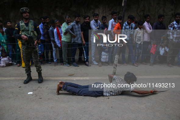 A man is prostrating past Hindu devotees queuing to pay their obeisance on the occasion of the Raksha Bandhan festival at the Shankaracharya...