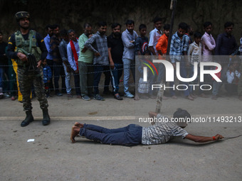 A man is prostrating past Hindu devotees queuing to pay their obeisance on the occasion of the Raksha Bandhan festival at the Shankaracharya...