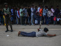 A man is prostrating past Hindu devotees queuing to pay their obeisance on the occasion of the Raksha Bandhan festival at the Shankaracharya...