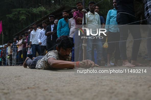 A man is prostrating past Hindu devotees queuing to pay their obeisance on the occasion of the Raksha Bandhan festival at the Shankaracharya...