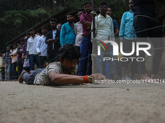 A man is prostrating past Hindu devotees queuing to pay their obeisance on the occasion of the Raksha Bandhan festival at the Shankaracharya...