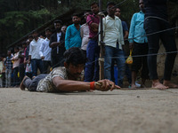 A man is prostrating past Hindu devotees queuing to pay their obeisance on the occasion of the Raksha Bandhan festival at the Shankaracharya...