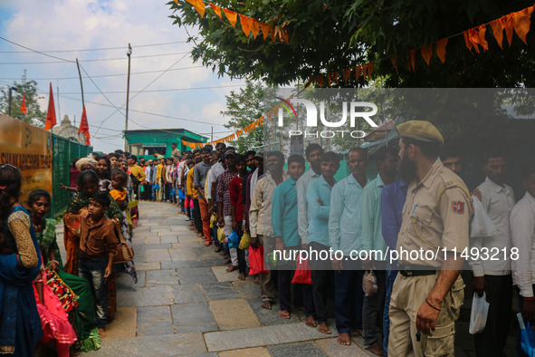 An Indian policeman is standing guard as Hindu devotees are arriving to pay obeisance on the occasion of the Raksha Bandhan festival at the...