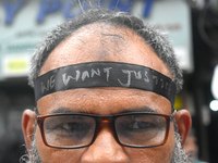 A doctor is tying a black ribbon on his forehead printed with ''we want justice'' during a protest rally for the R G Kar Medical College wom...