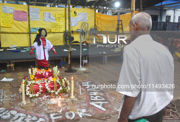 A person is standing in front of a clay statue of a doctor depicting a victim of rape and murder at a protest site in Kolkata, India, on Aug...