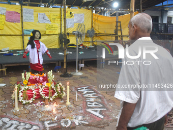 A person is standing in front of a clay statue of a doctor depicting a victim of rape and murder at a protest site in Kolkata, India, on Aug...