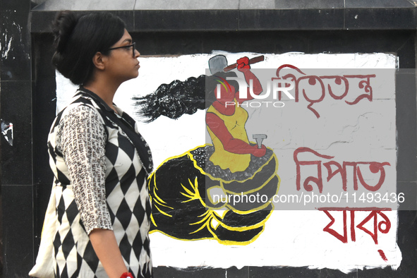 A woman is passing next to a mural with slogans inside Kolkata Medical College and Hospital campus condemning the rape and murder of a train...