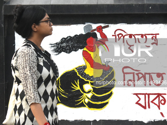 A woman is passing next to a mural with slogans inside Kolkata Medical College and Hospital campus condemning the rape and murder of a train...