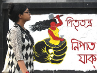 A woman is passing next to a mural with slogans inside Kolkata Medical College and Hospital campus condemning the rape and murder of a train...