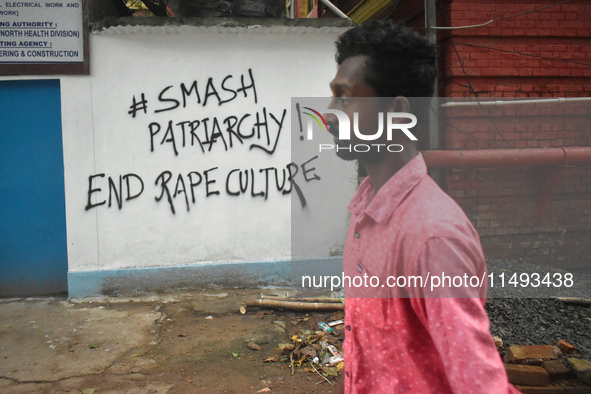 A person is passing next to a mural with slogans inside Kolkata Medical College and Hospital campus condemning the rape and murder of a trai...