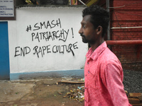 A person is passing next to a mural with slogans inside Kolkata Medical College and Hospital campus condemning the rape and murder of a trai...