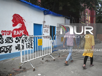 People are passing next to a mural with slogans inside Kolkata Medical College and Hospital campus condemning the rape and murder of a train...