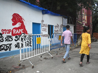 People are passing next to a mural with slogans inside Kolkata Medical College and Hospital campus condemning the rape and murder of a train...