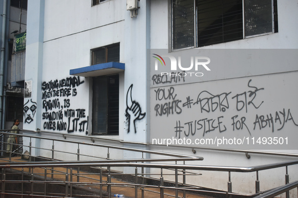 A woman is passing next to a mural with slogans inside Kolkata Medical College and Hospital campus condemning the rape and murder of a train...