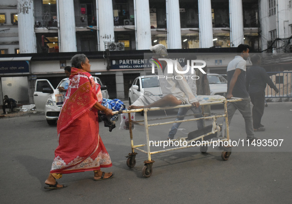 Patient relatives are carrying a patient into a trolley during a junior doctor strike to protest the rape and murder of a PGT woman doctor a...