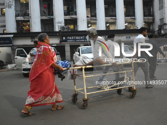 Patient relatives are carrying a patient into a trolley during a junior doctor strike to protest the rape and murder of a PGT woman doctor a...