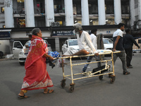 Patient relatives are carrying a patient into a trolley during a junior doctor strike to protest the rape and murder of a PGT woman doctor a...