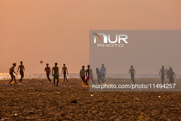 Youth are playing a game of football (soccer) by the ocean at sunset along Paruthiyoor Beach in Paruthiyoor, Kerala, India, on April 15, 202...