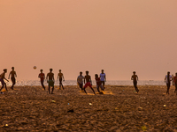 Youth are playing a game of football (soccer) by the ocean at sunset along Paruthiyoor Beach in Paruthiyoor, Kerala, India, on April 15, 202...