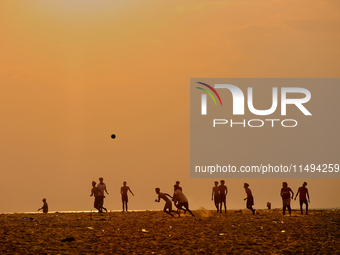 Youth are playing a game of football (soccer) by the ocean at sunset along Paruthiyoor Beach in Paruthiyoor, Kerala, India, on April 15, 202...