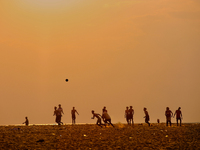 Youth are playing a game of football (soccer) by the ocean at sunset along Paruthiyoor Beach in Paruthiyoor, Kerala, India, on April 15, 202...