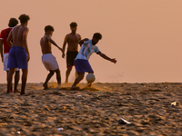 Youth are playing a game of football (soccer) by the ocean at sunset along Paruthiyoor Beach in Paruthiyoor, Kerala, India, on April 15, 202...