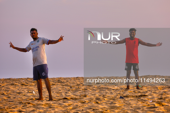 Youth are playing a game of football (soccer) by the ocean at sunset along Paruthiyoor Beach in Paruthiyoor, Kerala, India, on April 15, 202...