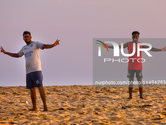 Youth are playing a game of football (soccer) by the ocean at sunset along Paruthiyoor Beach in Paruthiyoor, Kerala, India, on April 15, 202...