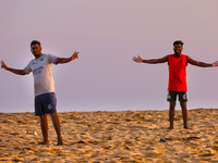 Youth are playing a game of football (soccer) by the ocean at sunset along Paruthiyoor Beach in Paruthiyoor, Kerala, India, on April 15, 202...