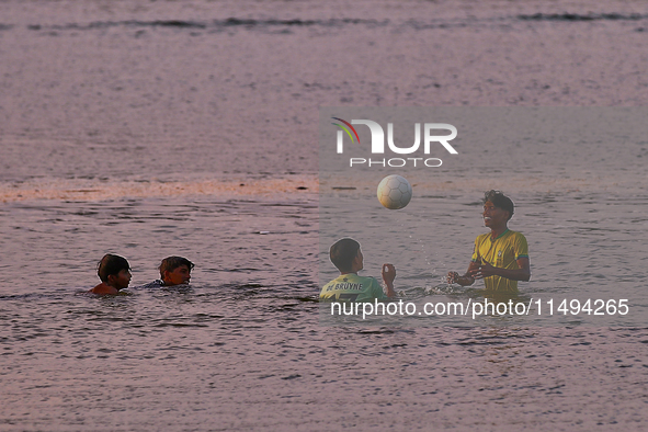 Youth are playing a game of football (soccer) by the ocean at sunset along Paruthiyoor Beach in Paruthiyoor, Kerala, India, on April 15, 202...