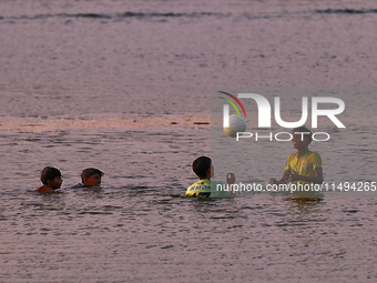 Youth are playing a game of football (soccer) by the ocean at sunset along Paruthiyoor Beach in Paruthiyoor, Kerala, India, on April 15, 202...