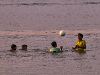 Youth are playing a game of football (soccer) by the ocean at sunset along Paruthiyoor Beach in Paruthiyoor, Kerala, India, on April 15, 202...