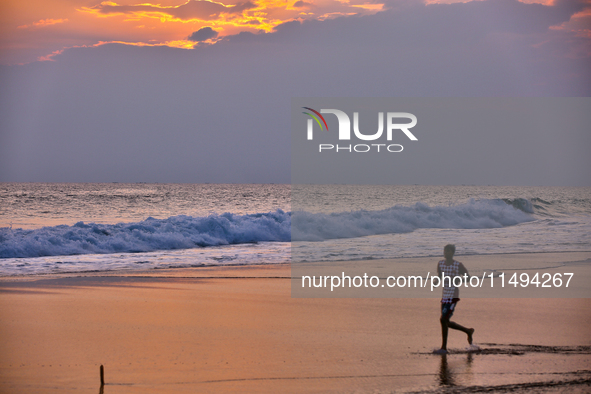 Youth are playing a game of football (soccer) by the ocean at sunset along Paruthiyoor Beach in Paruthiyoor, Kerala, India, on April 15, 202...