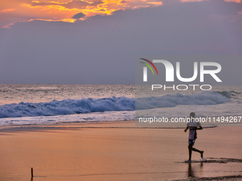 Youth are playing a game of football (soccer) by the ocean at sunset along Paruthiyoor Beach in Paruthiyoor, Kerala, India, on April 15, 202...