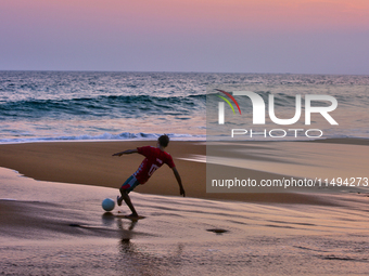 Youth are playing a game of football (soccer) by the ocean at sunset along Paruthiyoor Beach in Paruthiyoor, Kerala, India, on April 15, 202...