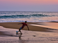 Youth are playing a game of football (soccer) by the ocean at sunset along Paruthiyoor Beach in Paruthiyoor, Kerala, India, on April 15, 202...