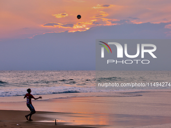 Youth are playing a game of football (soccer) by the ocean at sunset along Paruthiyoor Beach in Paruthiyoor, Kerala, India, on April 15, 202...