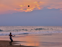 Youth are playing a game of football (soccer) by the ocean at sunset along Paruthiyoor Beach in Paruthiyoor, Kerala, India, on April 15, 202...