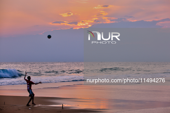 Youth are playing a game of football (soccer) by the ocean at sunset along Paruthiyoor Beach in Paruthiyoor, Kerala, India, on April 15, 202...