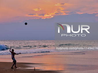 Youth are playing a game of football (soccer) by the ocean at sunset along Paruthiyoor Beach in Paruthiyoor, Kerala, India, on April 15, 202...