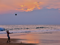 Youth are playing a game of football (soccer) by the ocean at sunset along Paruthiyoor Beach in Paruthiyoor, Kerala, India, on April 15, 202...