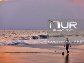 Youth are playing a game of football (soccer) by the ocean at sunset along Paruthiyoor Beach in Paruthiyoor, Kerala, India, on April 15, 202...