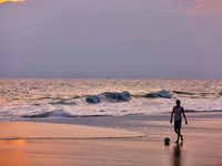 Youth are playing a game of football (soccer) by the ocean at sunset along Paruthiyoor Beach in Paruthiyoor, Kerala, India, on April 15, 202...