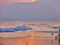 Youth are playing a game of football (soccer) by the ocean at sunset along Paruthiyoor Beach in Paruthiyoor, Kerala, India, on April 15, 202...