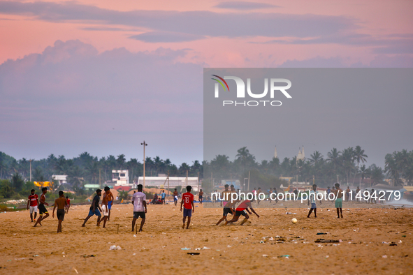 Youth are playing a game of football (soccer) by the ocean at sunset along Paruthiyoor Beach in Paruthiyoor, Kerala, India, on April 15, 202...