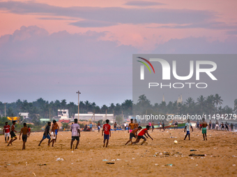 Youth are playing a game of football (soccer) by the ocean at sunset along Paruthiyoor Beach in Paruthiyoor, Kerala, India, on April 15, 202...